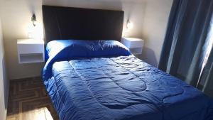 een bed met een blauw dekbed in een slaapkamer bij CABAÑAS MAY . in San Rafael
