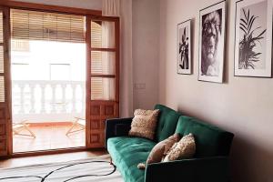 a living room with a green couch and a window at Serendipia: tu hogar en este blanco pueblo in Frigiliana