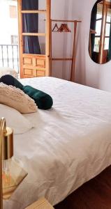 a white bed in a room with a mirror at Serendipia: tu hogar en este blanco pueblo in Frigiliana