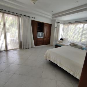 a bedroom with a large white bed and large windows at Condominio El Peñon in Girardot
