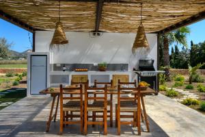 an outdoor kitchen with a wooden table and chairs at Villa Can Jaume Arabí de Baix in Puig D’en Valls