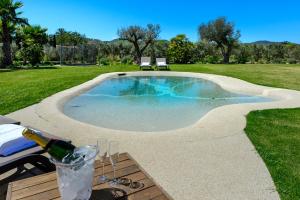 a swimming pool in a yard with a bottle of champagne at Villa Can Jaume Arabí de Baix in Puig D’en Valls