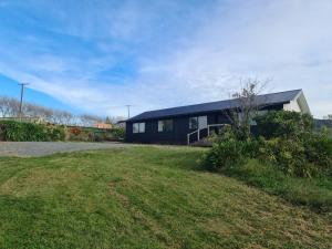 a black house with a grass yard in front of it at Tavis Burn Cottage on Maungatautari Mountain in Karapiro