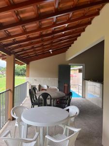 d'une terrasse avec des tables et des chaises blanches et un plafond en bois. dans l'établissement Chácara Toca do Oliveira, à Socorro