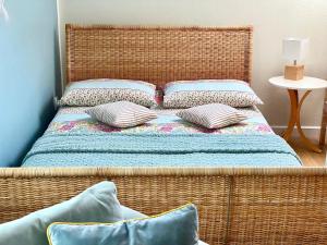 wiklinowe łóżko z poduszkami w pokoju w obiekcie Szary Domek Apartamenty Ustka w Ustce