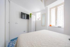 una camera bianca con un letto e una TV a parete di YourHome - Lorena Maria House Positano a Positano