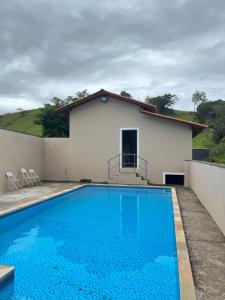 a villa with a swimming pool in front of a house at Chácara Toca do Oliveira in Socorro
