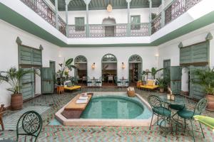 una piscina cubierta en una gran sala con mesas y sillas en Riad Agathe & Spa, en Marrakech