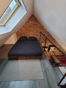 a loft bed in a room with a brick wall at Le Cosy in Bohain-en-Vermandois