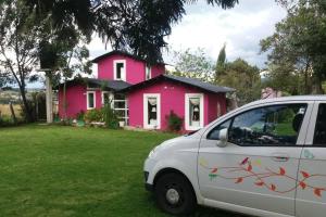 a white car parked in front of a pink house at Cabaña Campestre Flamingo Paipa Boyaca in Paipa