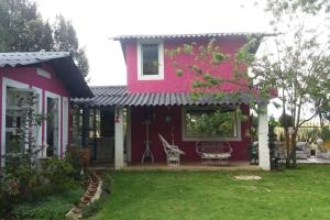 ein rosafarbenes Haus mit einer Terrasse und einem Hof in der Unterkunft Suite Campestre Flamingo Paipa Boyaca in Paipa