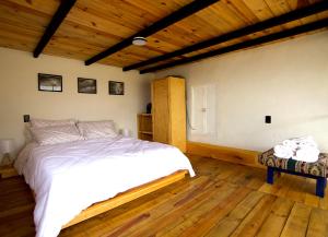 um quarto com uma cama branca e piso em madeira em Piedra de Cobre em Tepoztlán