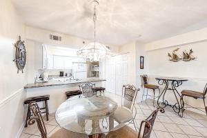 a kitchen and dining room with a glass table and chairs at Four Winds 102 in Orange Beach