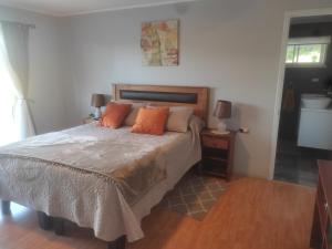1 dormitorio con 1 cama con almohadas de color naranja en Casa de campo en Curacautín