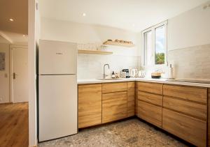 La cuisine est équipée d'un réfrigérateur blanc et de placards en bois. dans l'établissement Magnifique 3 pièces - Proximité Place des Lices avec parking, à Saint-Tropez