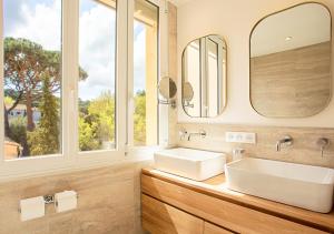 La salle de bains est pourvue de 2 lavabos et d'un grand miroir. dans l'établissement Magnifique 3 pièces - Proximité Place des Lices avec parking, à Saint-Tropez