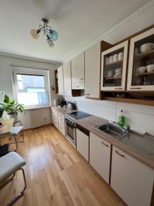 a kitchen with white cabinets and a wooden floor at Apartament Acasa in Spielberg