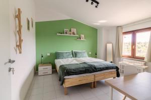 Dormitorio verde con cama y mesa en Maeva Guesthouse, en Puegnago sul Garda