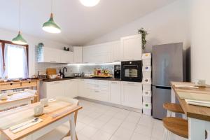cocina con armarios blancos y nevera de acero inoxidable en Maeva Guesthouse, en Puegnago sul Garda