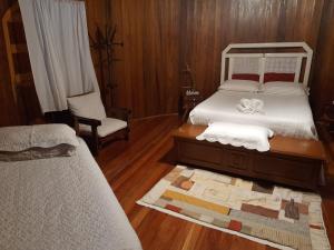 - une chambre avec deux lits et une chaise dans l'établissement Recanto das Pipas - Hospedagem Diferenciada, à São Valentim do Sul