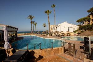 una grande piscina con palme e l'oceano di Fantastic Sea View Apartament DOÑA LOLA a Mijas