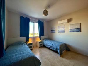 a bedroom with two beds and a window with blue curtains at Reihenhaus in Tersefanou in Tersephanou