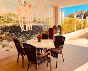 un comedor con mesa, sillas y una pintura en Linc Rooms & Apartments, en Banjole
