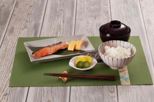 ホテルDEN في طوكيو: طبق من السوشي و صحن من الرز و عيدان الاكل