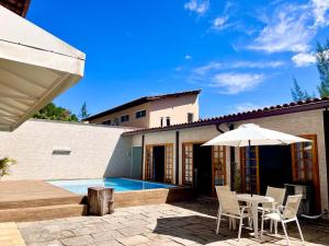 un patio con mesa, sillas y sombrilla en Casa Chalé na Barra da Tijuca Com Piscina Próximo a Praia, en Río de Janeiro