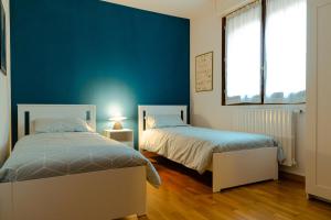 1 dormitorio con 2 camas y pared azul en Il Giardino di Boccaccio, en Castenaso