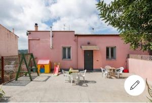 ein rosafarbenes Haus mit Tischen und Stühlen davor in der Unterkunft Albero della musica in Sassari