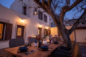 a wooden table with wine glasses and a tree at Walnut tree Villa Ano Archanes-10km from Heraklion in Epáno Arkhánai