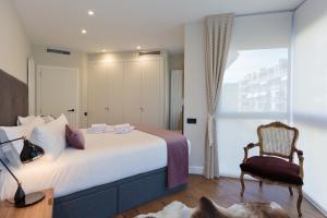 バルセロナにあるRAMBLA POBLENOU Luxuryのベッドルーム1室(ベッド1台、椅子、窓付)