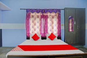 Schlafzimmer mit einem Bett mit roten Kissen und einem Fenster in der Unterkunft OYO Flagship Hotel Baba''s House in Kakarmatha