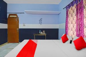 ein Schlafzimmer mit einem Bett mit roten Kissen in der Unterkunft OYO Flagship Hotel Baba''s House in Kakarmatha