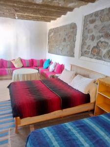 a bedroom with a large bed and a couch at Gîte El houmar in Tanakoub