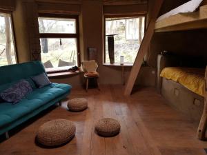 ein Wohnzimmer mit einem Sofa, einem Bett und Fenstern in der Unterkunft Lehmhaus in Templin