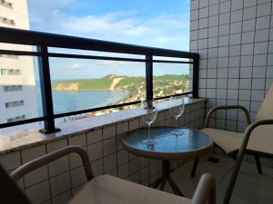 einen Balkon mit Tisch und 2 Weingläsern in der Unterkunft Ponta Negra Flats Confort ACCOMMODATIONS AMAQ 18 andar in Natal