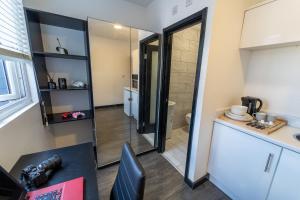 um quarto com uma cozinha, uma secretária e um lavatório. em Modern Studio 10 mins on train to City! em Birmingham