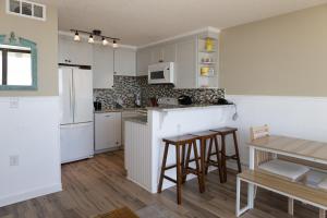 a kitchen with white cabinets and a table and chairs at 0412 Memories Made At The Beach by Atlantic Towers in Carolina Beach