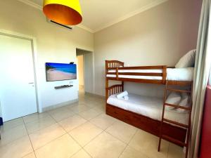 Laguna Lake House - Private Pool - King Bed - Sleeps 14 في بلايا بلانكا: غرفة بسريرين بطابقين وتلفزيون