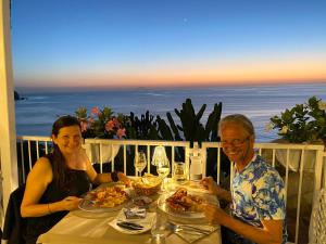 Ein Mann und eine Frau sitzen an einem Tisch mit Essen in der Unterkunft Mediterranean Boutique Hotel in Tropea