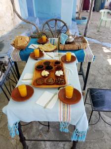 a table with a tray of donuts and orange cups at Gîte El houmar in Tanakoub