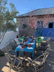 einen Tisch und Stühle mit einem blauen Tischtuch sowie einem Tisch und Stühlen in der Unterkunft Gîte El houmar in Tanakoub