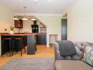 a living room with a couch and a kitchen at How Hill Farm Cottage in Penrith