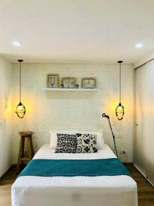 een slaapkamer met een bed met twee lampjes aan de muur bij Hermoso loft en el centro histórico de Bogotá. in Bogota