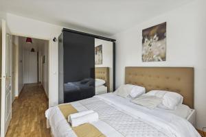 a bedroom with a large bed with white sheets at "Joie de vivre" - Parisian Spacious & Charming flat in Asnières-sur-Seine