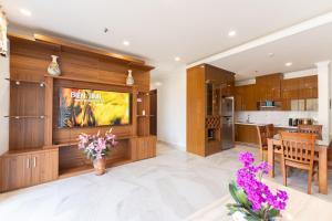 a living room with a large entertainment center and a kitchen at Homestay Sapphire 4br Hạ Long View Biển in Ha Long
