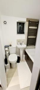 a bathroom with a toilet and a sink and a tub at Maple House - Inviting 1-Bed Apartment in London in London
