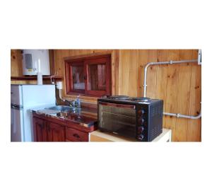 uma cozinha com um micro-ondas e um lavatório em Hermosa Cabaña Con Pileta em Chivilcoy